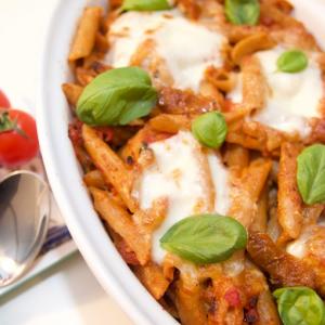 Cheesy pasta dish with vegetarian sausages and topped with mozzarella cheese and basil