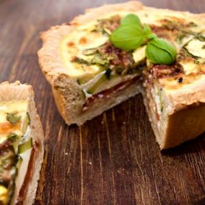 A delicious deep layered Mediterranean quiche with basil garnish